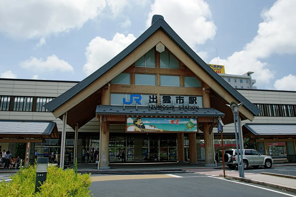 「JR 出雲市駅 IZUMOSHI STATION」の看板が掲げられた木造の大屋根を持つ駅舎正面玄関の写真
