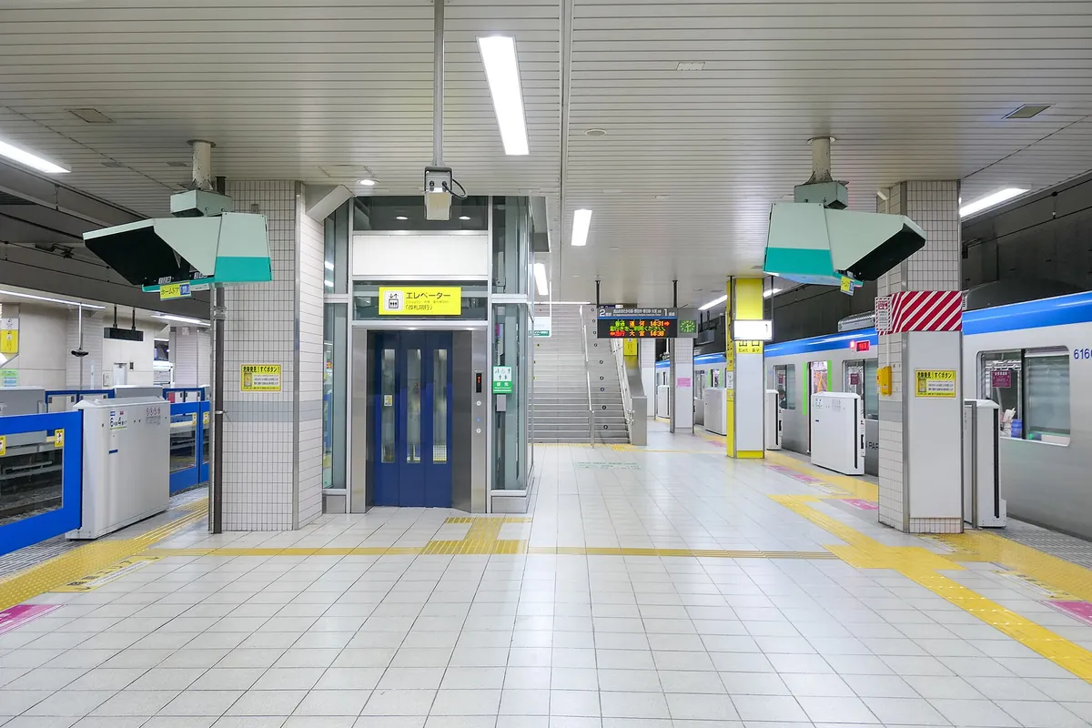 駅のホームでエレベーターと階段、発車案内の電光掲示板が並ぶ様子の写真