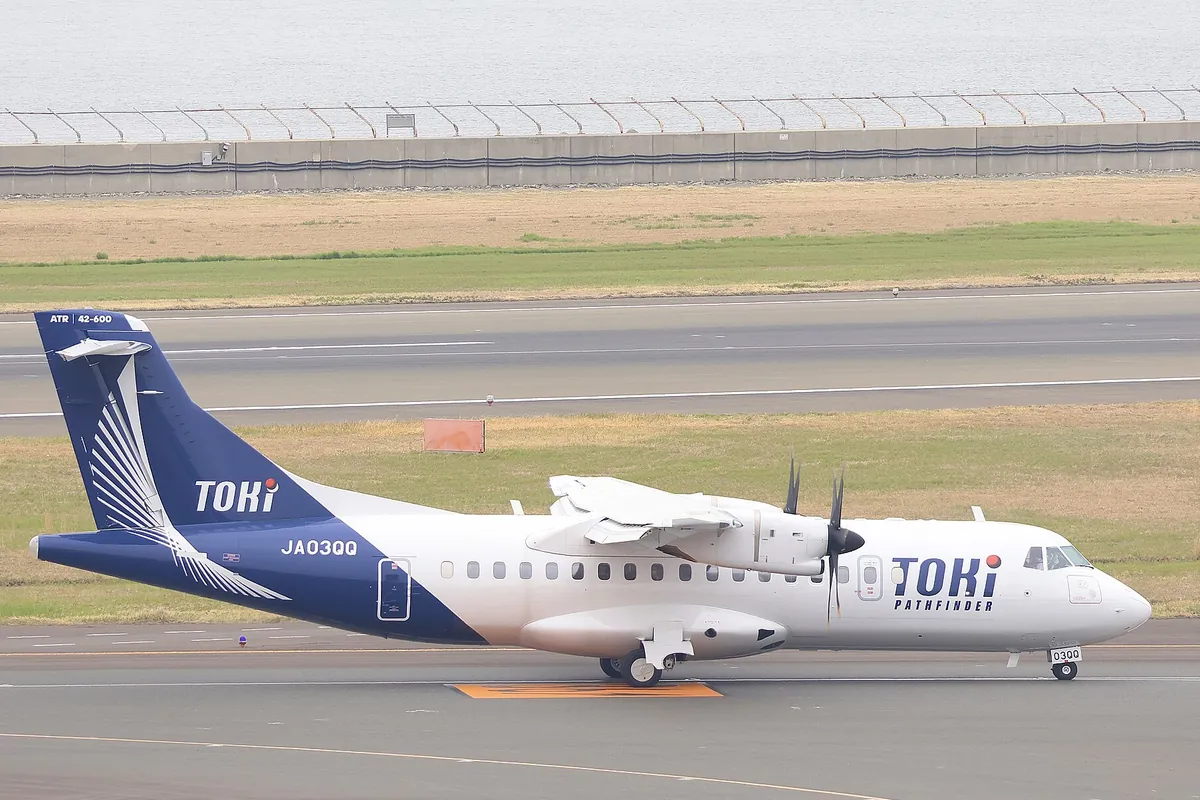 「TOKI」のロゴと機体記号JA03QQが見える青と白のATR機が滑走路を走行する様子の写真