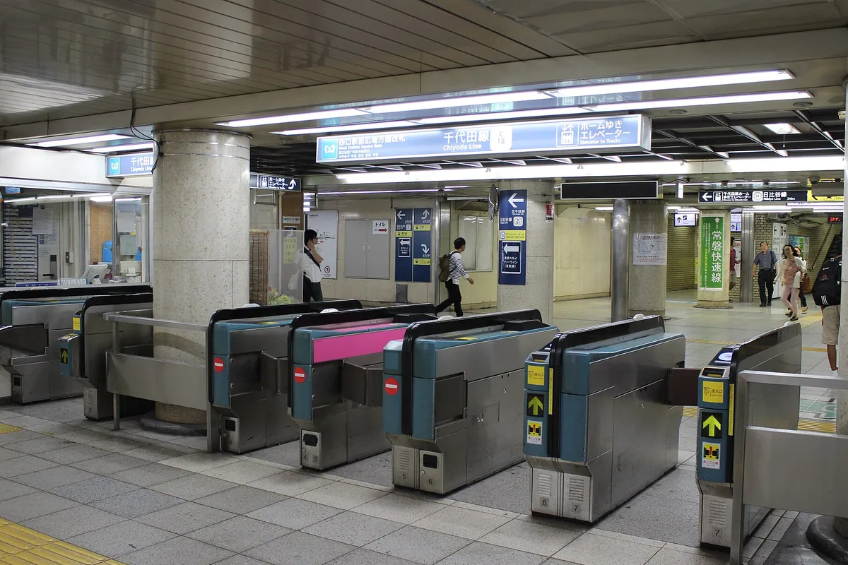 東京メトロ千代田線の改札口で、複数の自動改札機が並び奥に案内表示と利用客が写っている写真