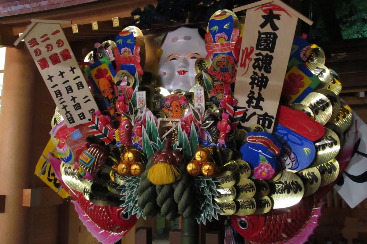 大國魂神社の熊手に、十一月二日・十四日・二十六日と書かれた木札や小判、福笹などの縁起物が飾られている写真