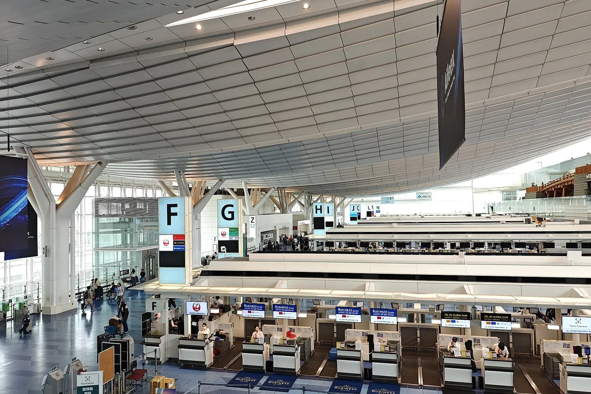 空港の出発ロビーで、F・Gなどのアルファベット表示とカウンターが並ぶ様子の写真