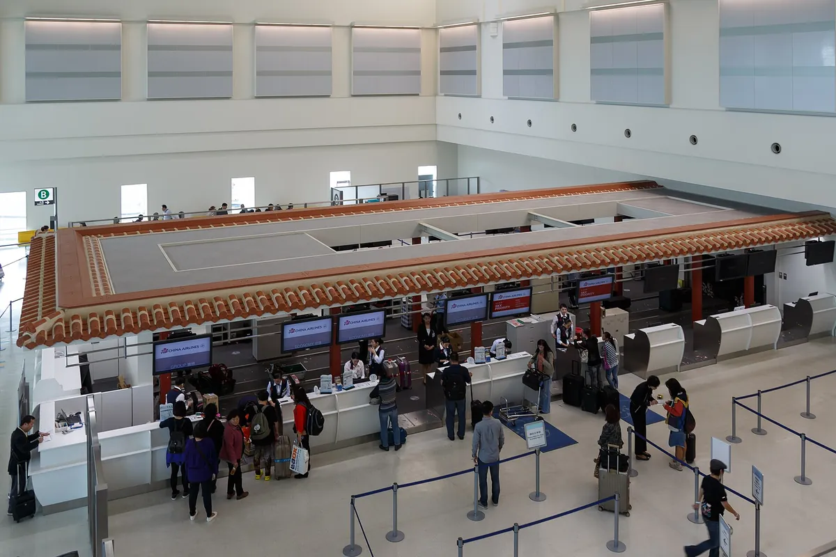 空港のターミナル出発ロビーで、航空会社のカウンターに利用客が並び手続きをしている様子の写真