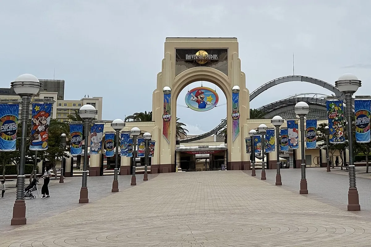 USJのパークエントランスゲートで、アーチ型の門にマリオなどのキャラクター装飾と「UNIVERSAL STUDIOS」の文字が見える写真