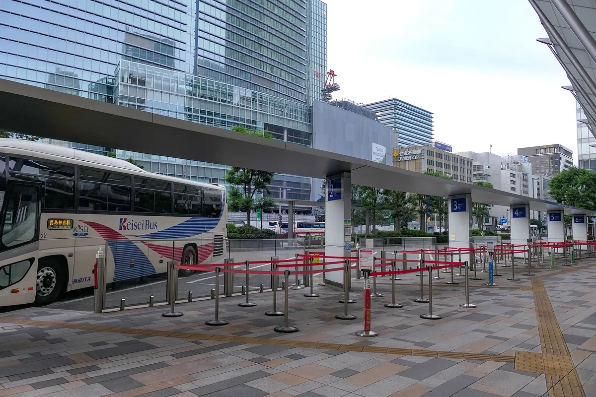 東京駅八重洲口のバスターミナルで、高速バスの乗り場に案内の看板とバス車両が並ぶ様子の写真