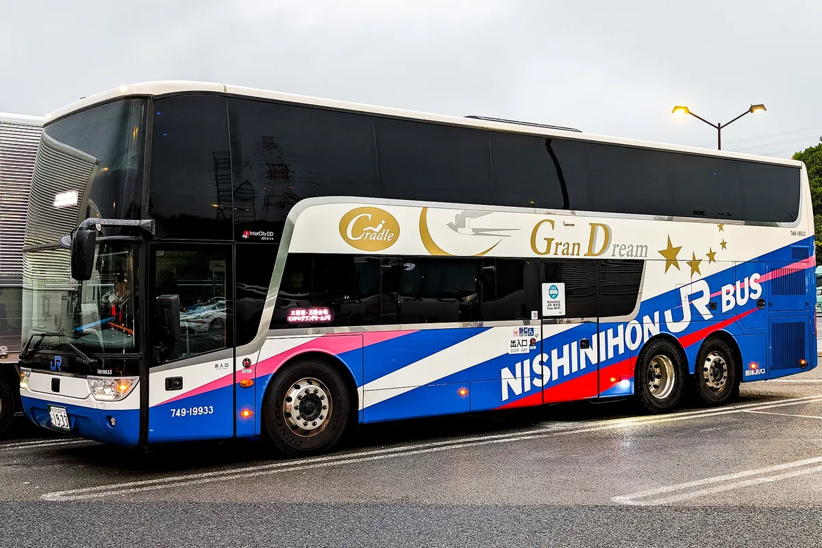「NISHINIHON JR BUS」と書かれたグランドリームの2階建て夜行バス車両を側面から写した写真