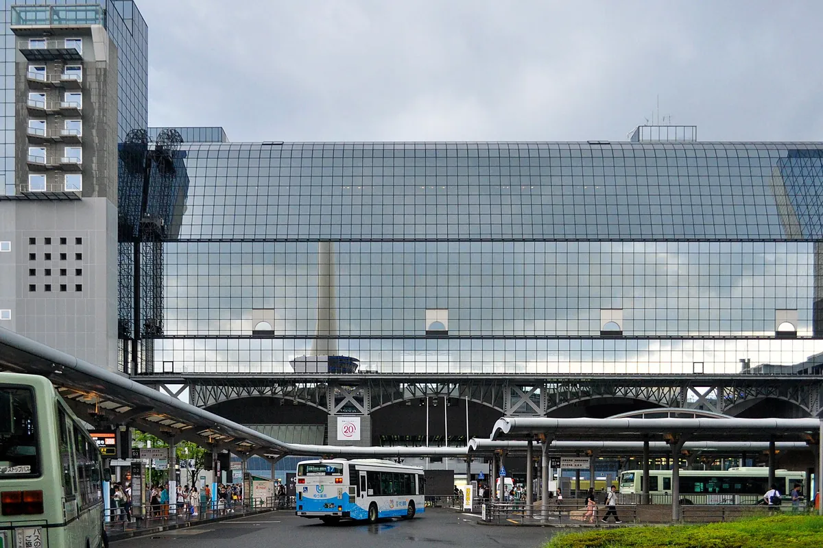 京都駅のガラス張りの駅舎を背景に、バスターミナルで路線バスが発着する様子の写真