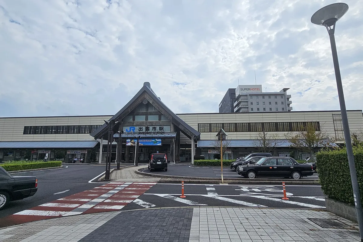 JR出雲市駅の駅舎正面を駅前ロータリーとタクシーが並ぶ様子とともに写した写真