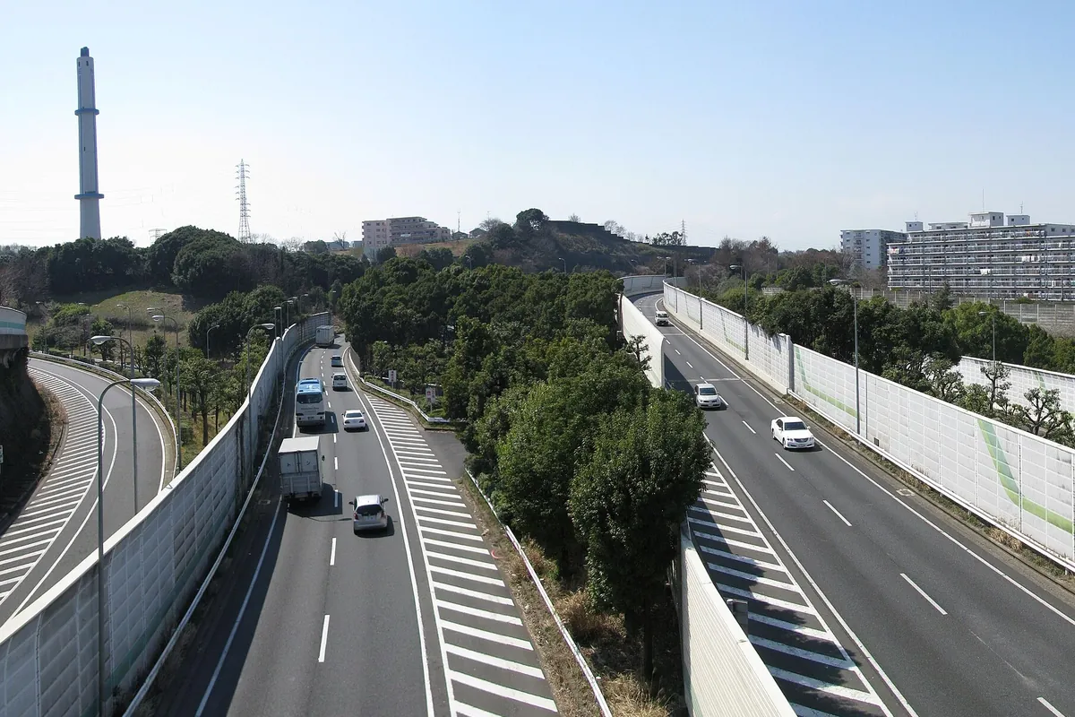 横浜横須賀道路の本線で、緑の遮音壁に囲まれた片側2車線を走行する複数の車両の写真